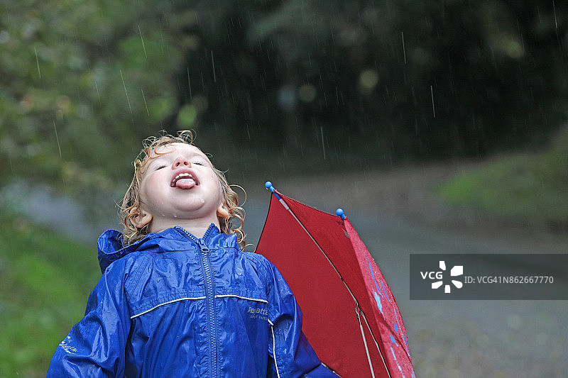 小女孩在户外用舌头接雨水图片素材