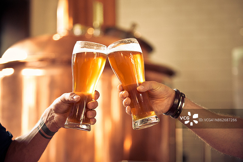 朋友们在精酿啤酒厂用啤酒杯敬酒图片素材