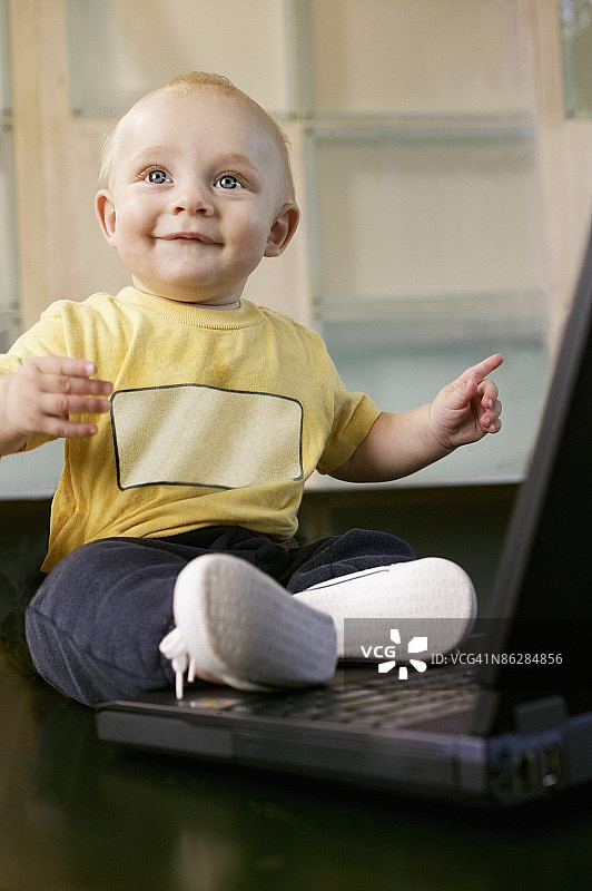 宝宝坐在笔记本电脑旁图片素材