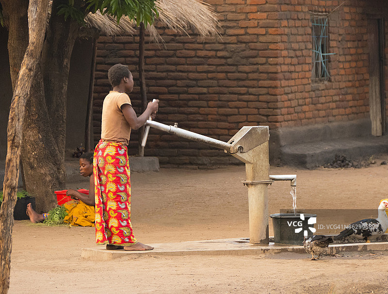马拉维萨利马村庄里抽水的传统非洲妇女图片素材