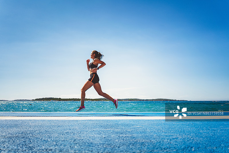 运动型女人在海岸边跑步图片素材