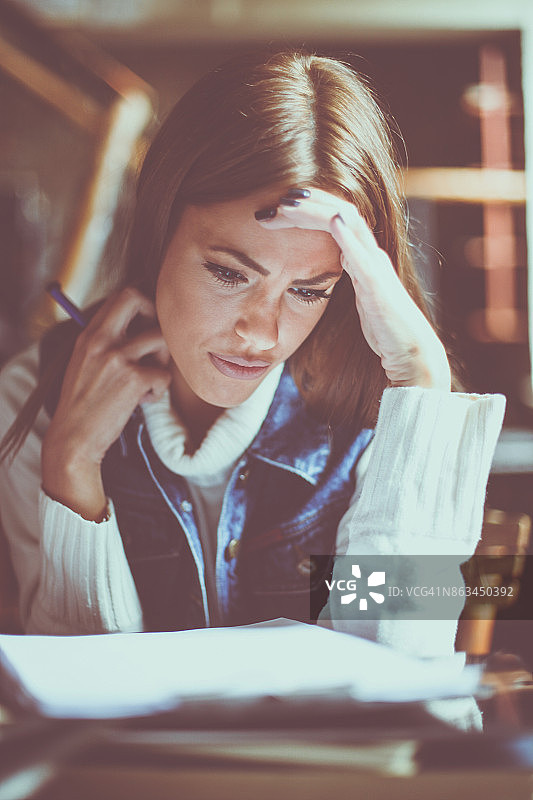 严肃的年轻女学生在家阅读文件学习图片素材