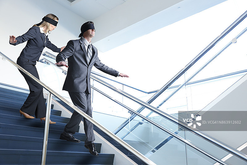 两个蒙眼人摸索着走楼梯图片素材