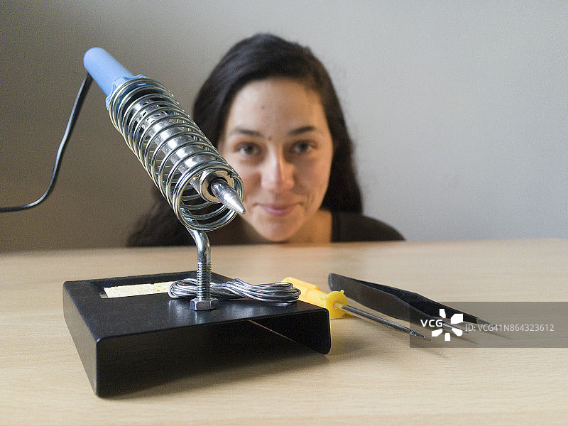 在木桌上使用电烙铁的女人图片素材