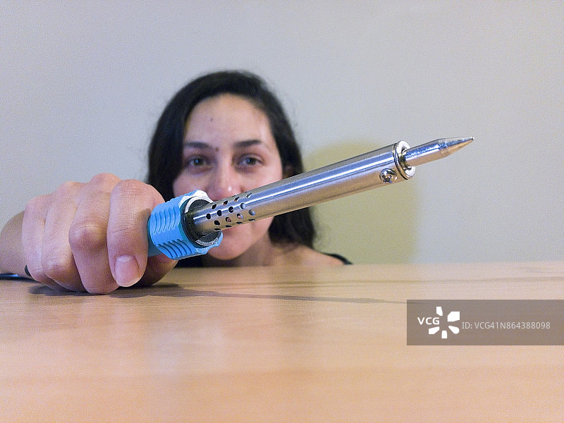 在木桌上使用电烙铁的女人图片素材