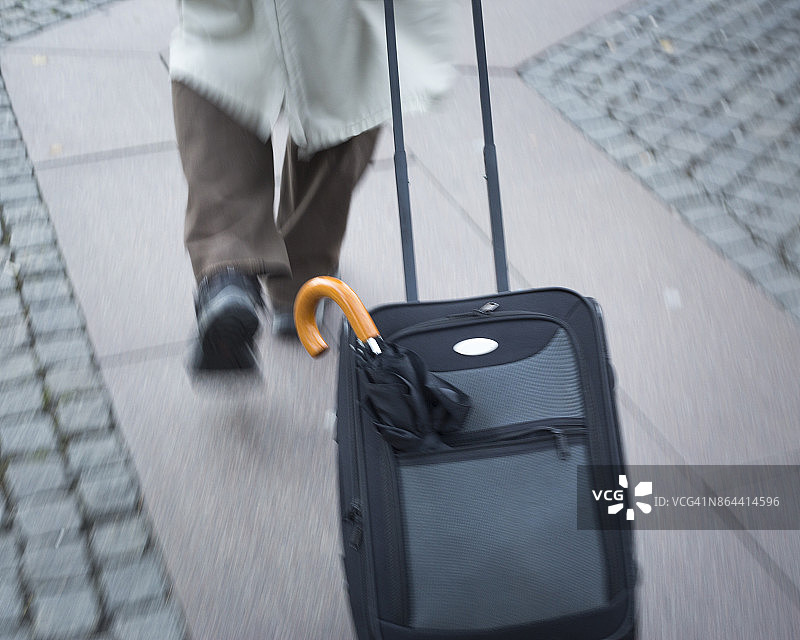 男人拉着行李箱走在瑞典马尔默图片素材