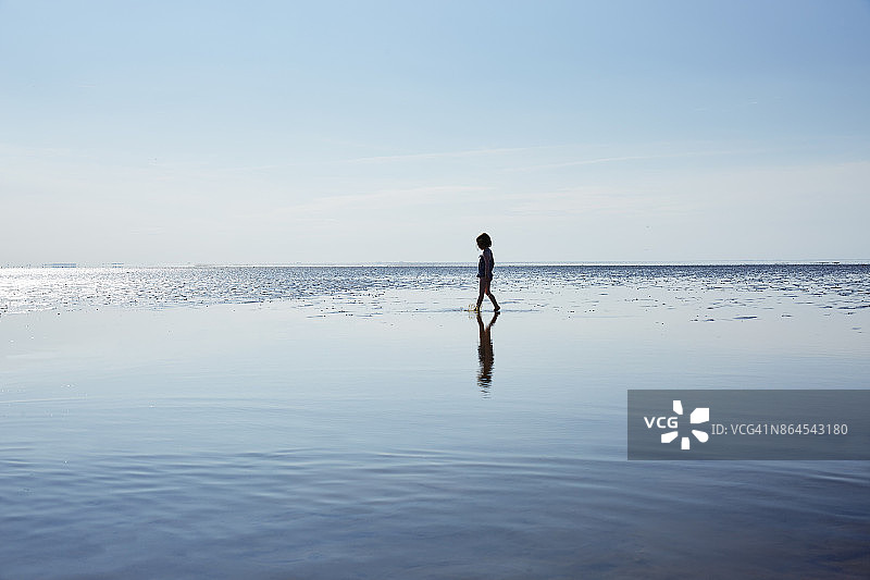 夏季在浅海中漫步的年轻女孩图片素材