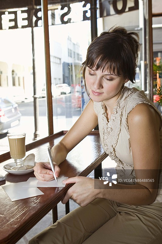 在咖啡馆写明信片的女人图片素材