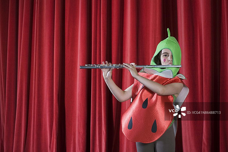 女孩在舞台上打扮成草莓演奏长笛图片素材