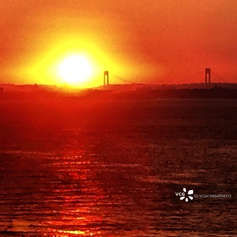 从纽约罗卡威海峡对面看到的维拉扎诺海峡大桥外的壮观日落图片素材