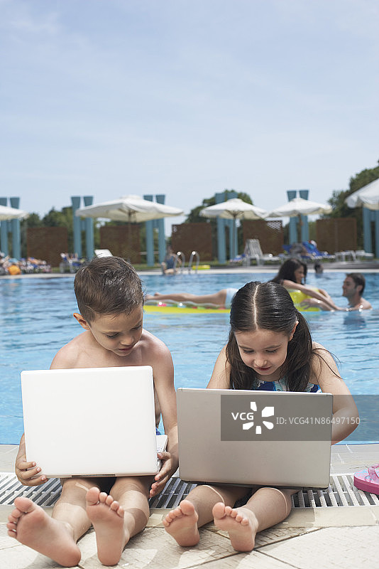 孩子们在泳池边使用笔记本电脑图片素材