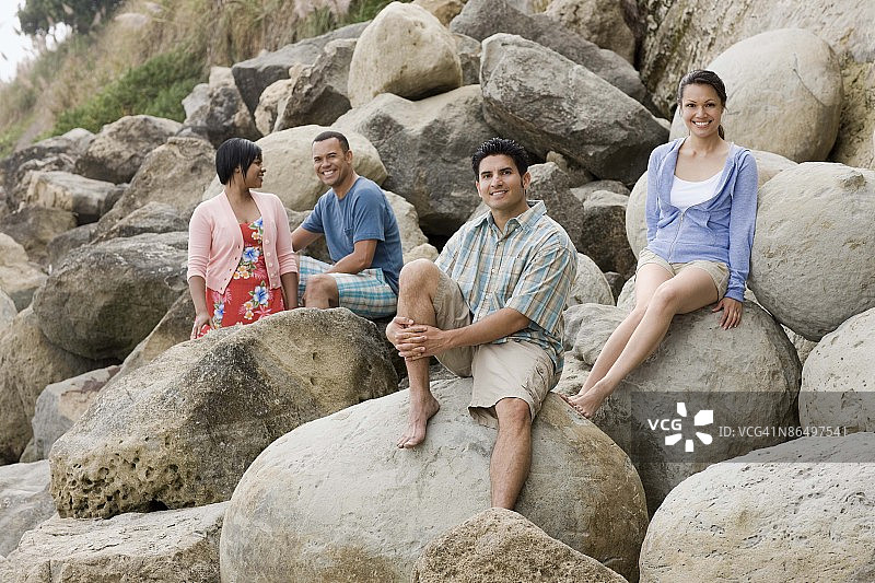 朋友们坐在加利福尼亚州圣克鲁斯岩石上图片素材