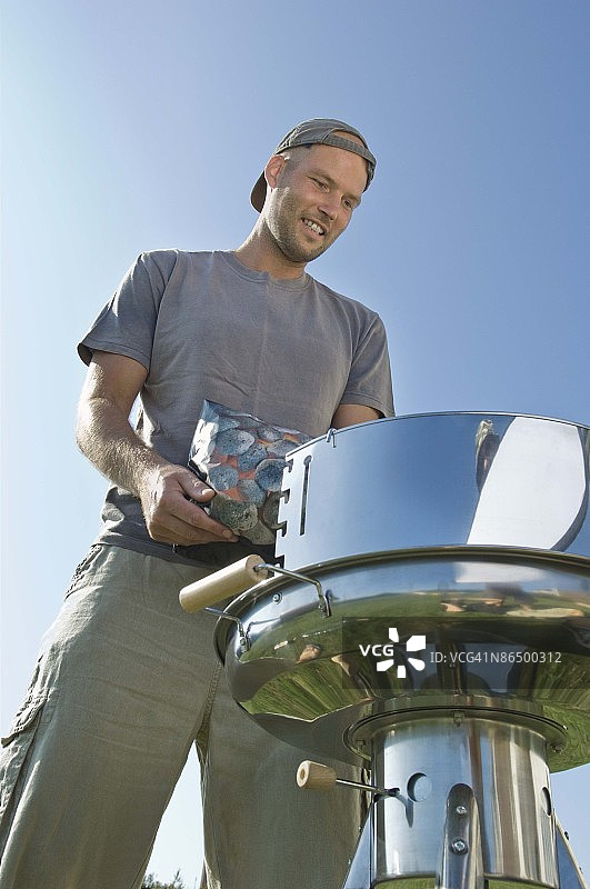 男人将木炭倒入烤架图片素材