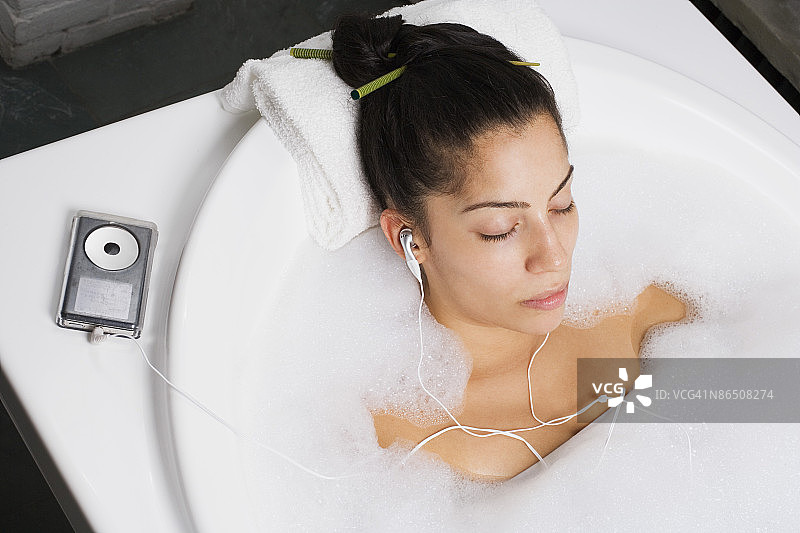 女人在泡泡浴中听音乐放松身心图片素材