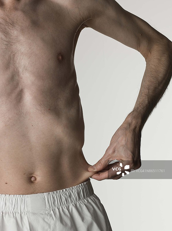 瘦弱男子捏着腰部皮肤图片素材