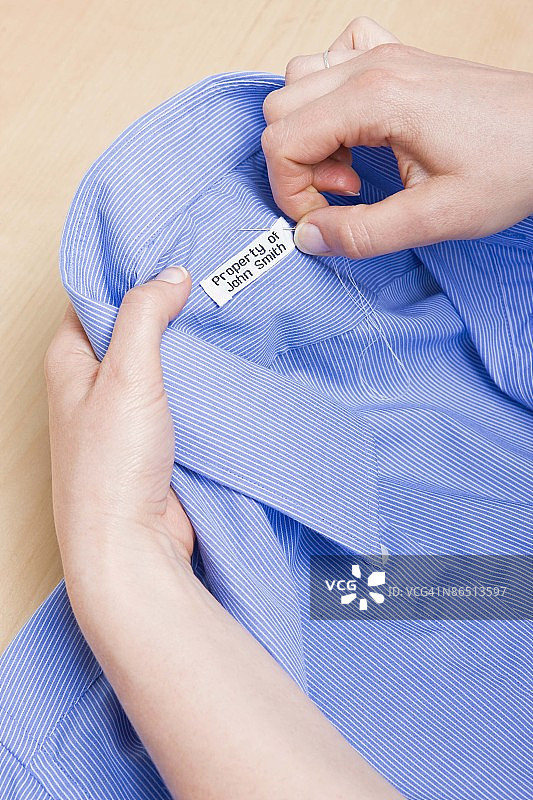 手将姓名标签缝到衬衫上图片素材
