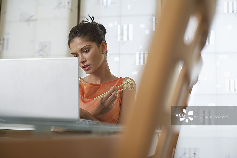 女人吃寿司并使用笔记本电脑图片素材