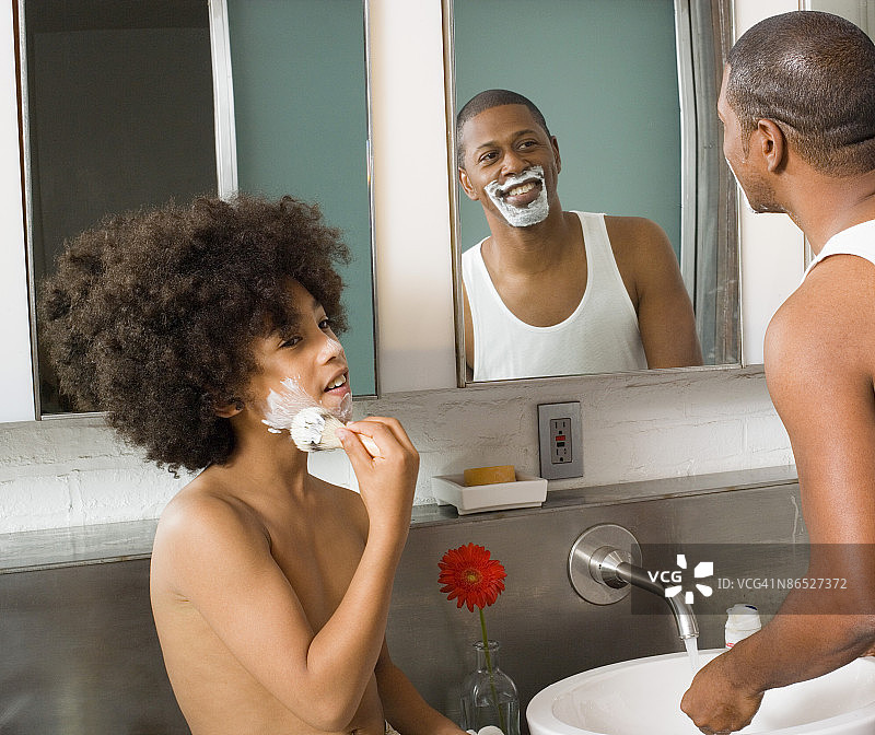 儿子在父亲刮胡子时涂抹剃须膏图片素材