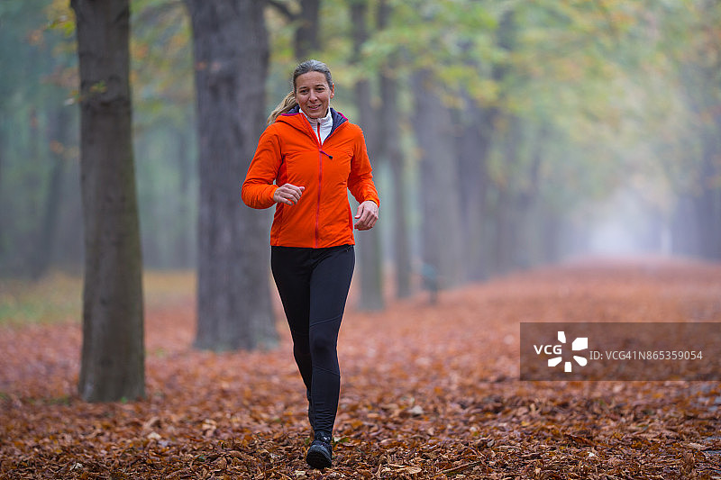 运动中的女性 - 阴天在公园慢跑的跑步装女性图片素材