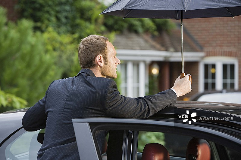 男人在车旁打着伞图片素材