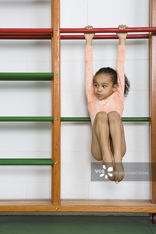 悬挂在单杠上的体操女孩图片素材