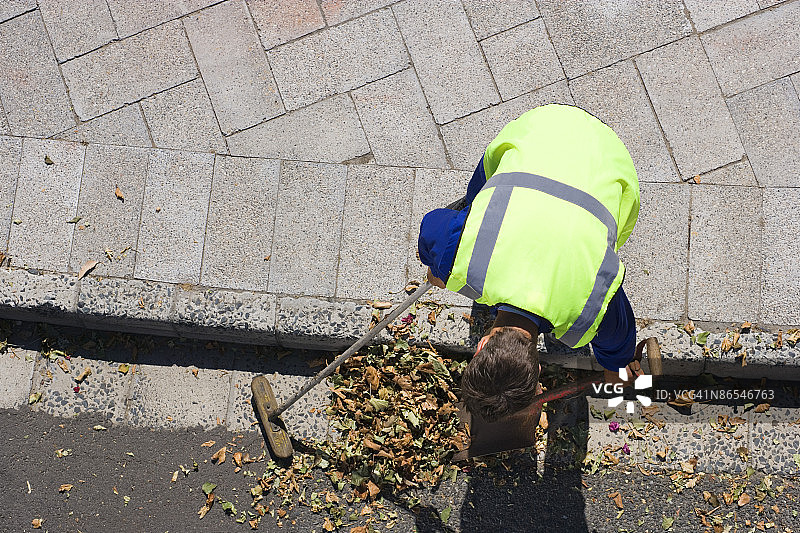 建筑工人在路边耙树叶图片素材