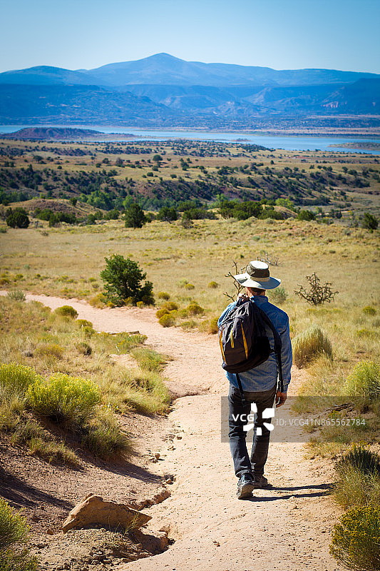 老年男人徒步旅行，背景是湖泊和山脉图片素材