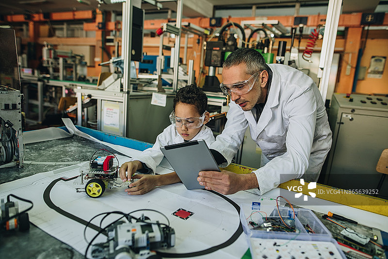 男老师和小男孩制作学校科学项目的机器人图片素材