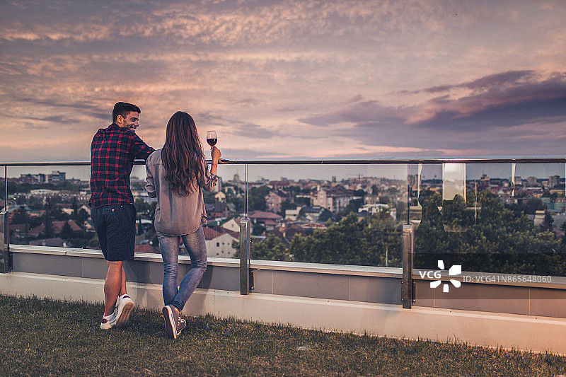 快乐情侣在顶层公寓阳台上交流的背影图片素材