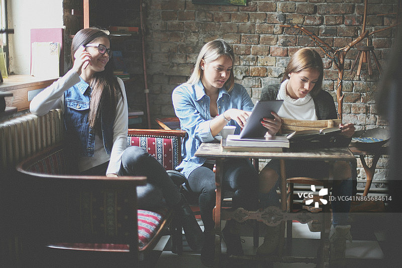 在图书馆里一起学习、使用手机的女孩们图片素材
