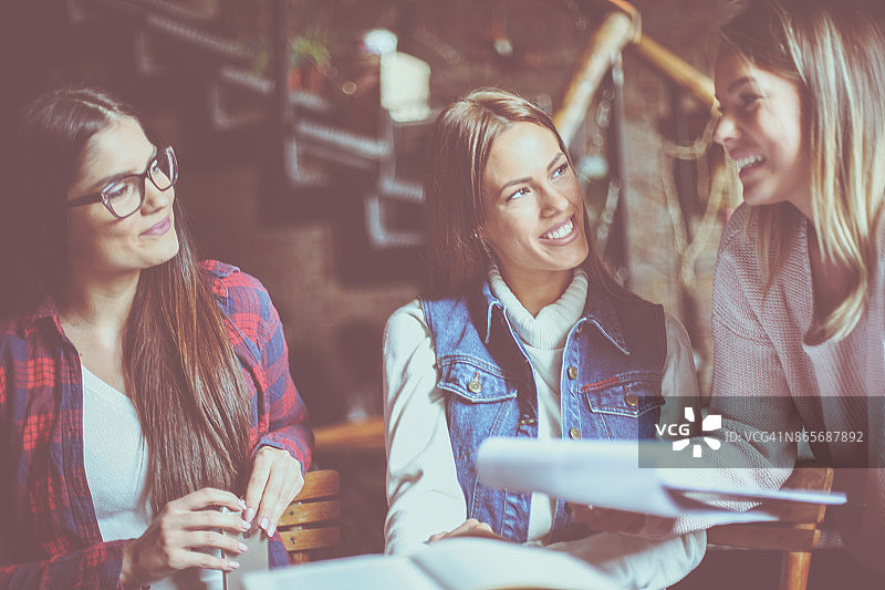 在咖啡馆里一起学习的快乐的年轻女学生。图片素材