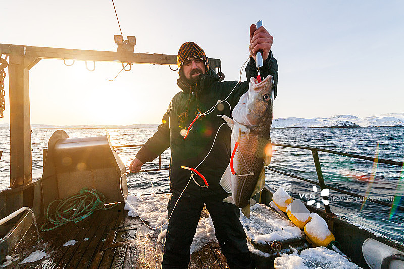 夕阳下拿着鳕鱼的渔夫图片素材