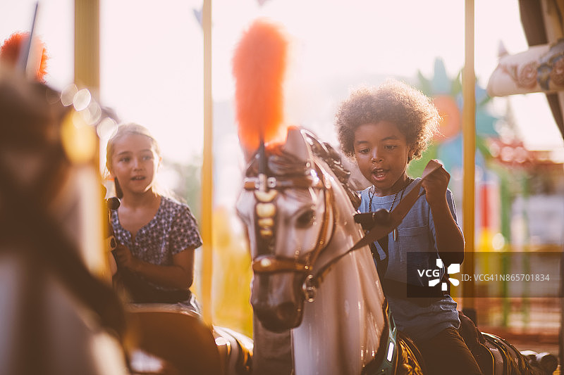 不同种族的孩子们在游乐园的旋转木马上玩耍图片素材