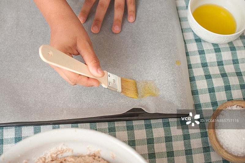 男孩的手在烘焙纸上抹油图片素材