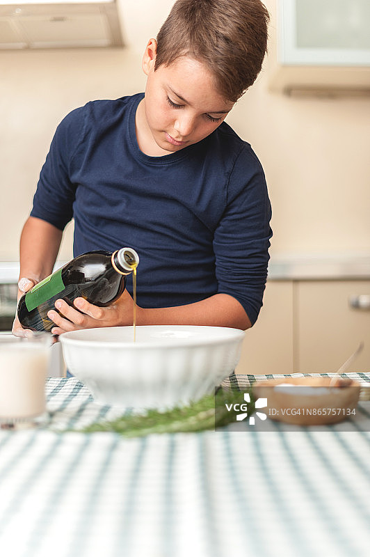 青少年男孩在碗里倒橄榄油图片素材