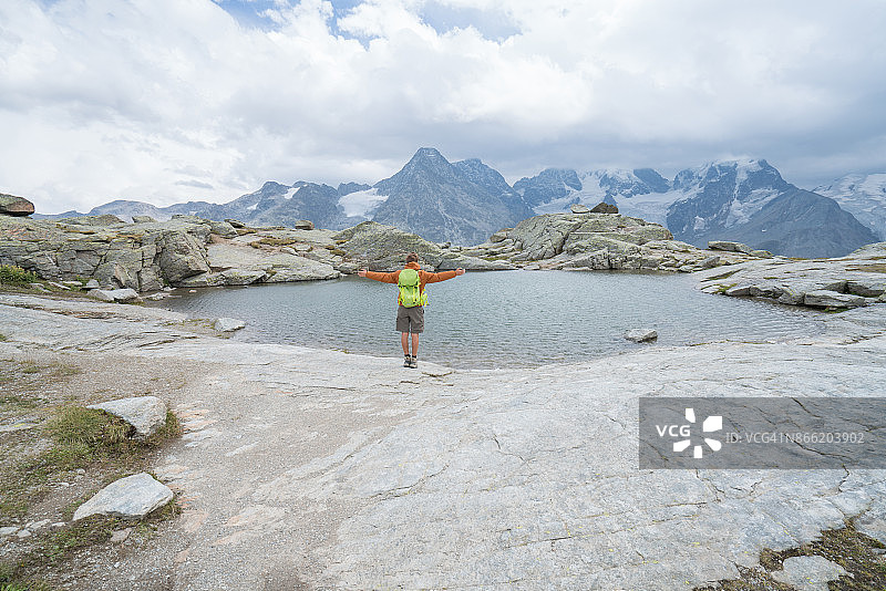 瑞士山顶上伸出双臂的男性徒步者图片素材