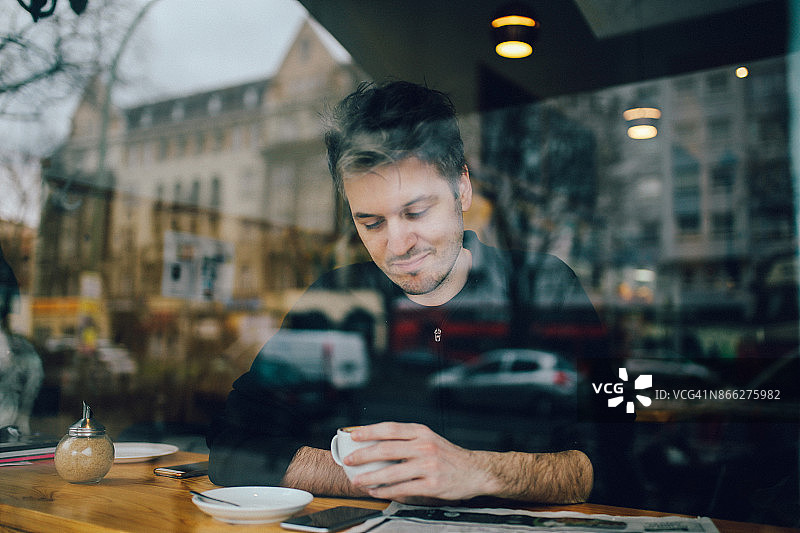 年轻男人在柏林咖啡馆里放松阅读报纸图片素材