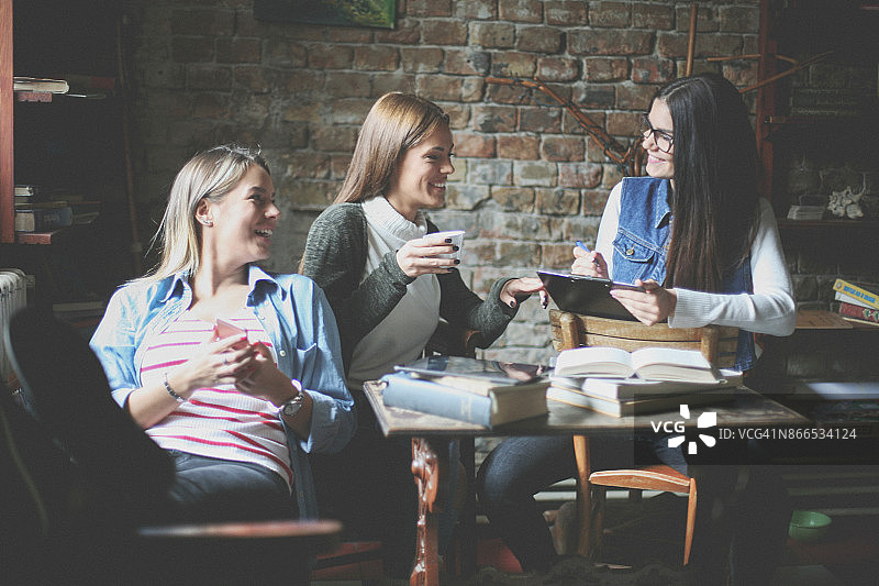 咖啡馆里进行有趣交谈的三个女学生图片素材