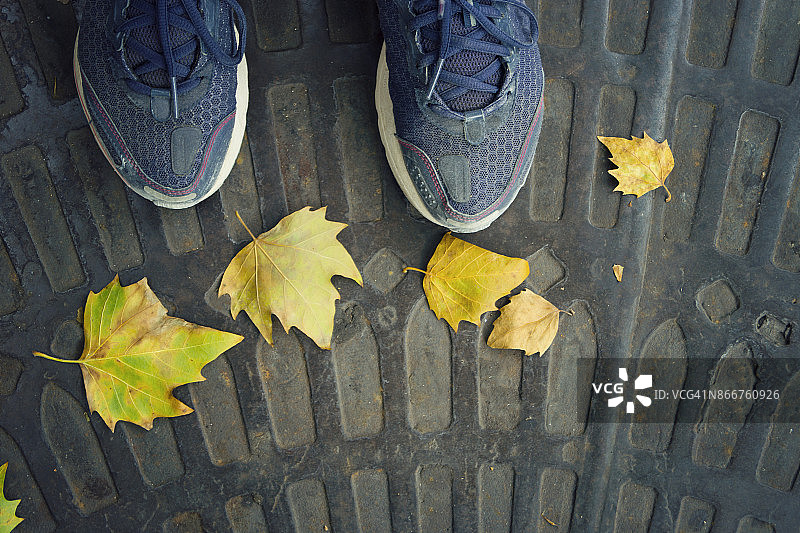 地板上的脚和第一片秋叶的个人视角图片素材