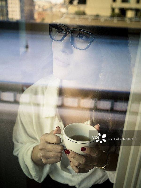 隔着玻璃窗看喝咖啡的女人图片素材