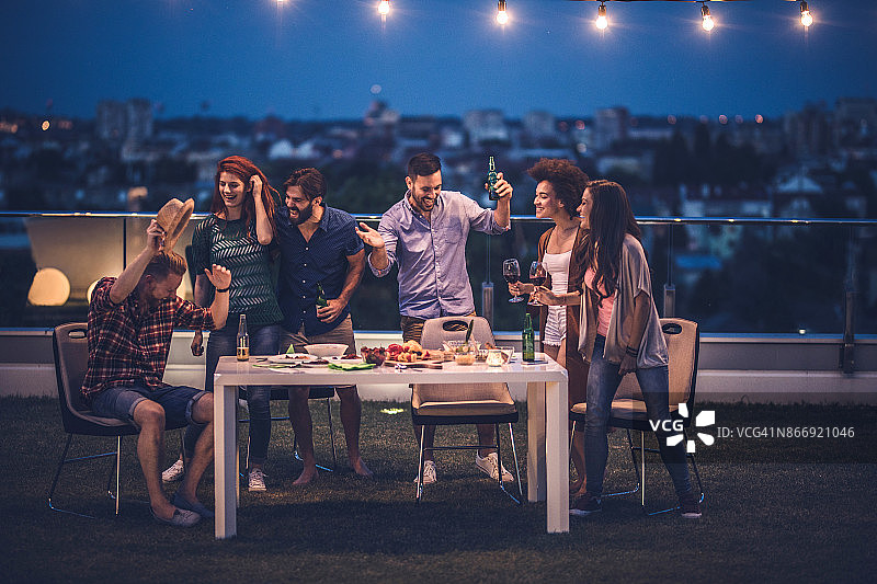 在顶层公寓阳台上参加派对的快乐朋友们图片素材