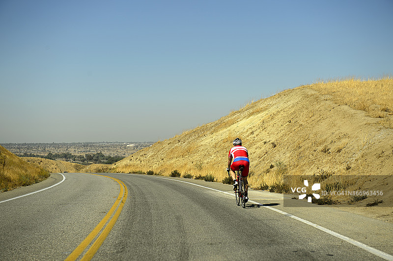 在美国加利福尼亚州贝克斯菲尔德附近的奥尔德代尔高速公路上骑自行车的男子图片素材