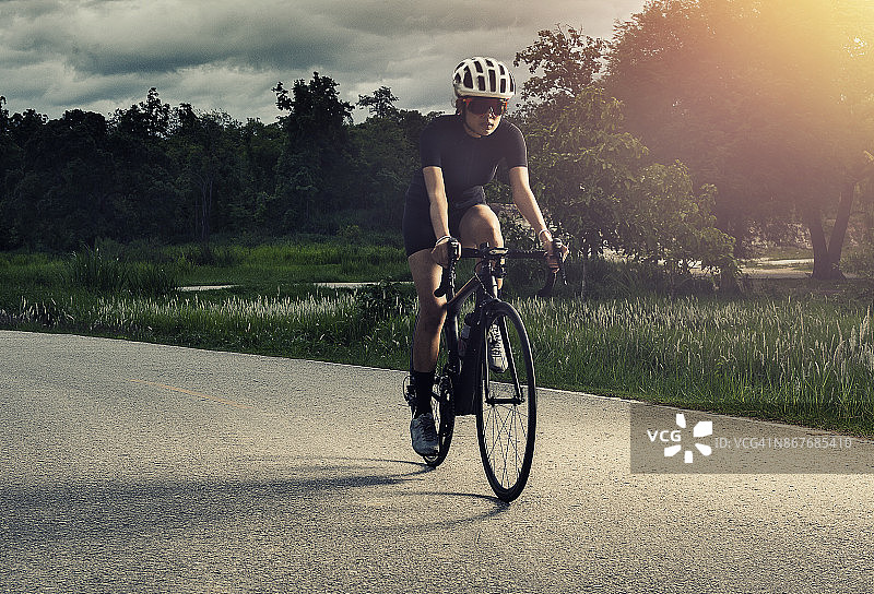 戴头盔的亚洲健康女孩在自行车道上骑行锻炼图片素材