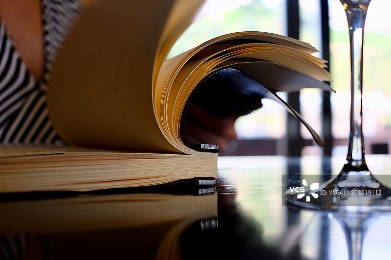 在餐厅，一位女士看着酒单，品尝着白葡萄酒图片素材