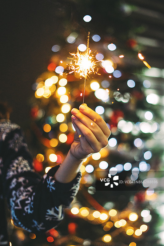 女子在圣诞树前手持烟花棒图片素材