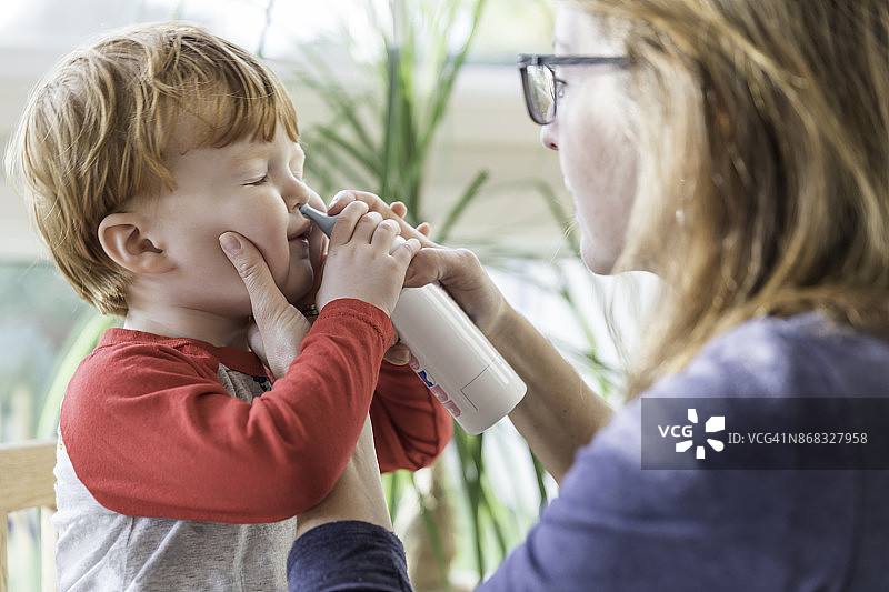 母亲用吸鼻器和生理盐水清洁宝宝的鼻子图片素材