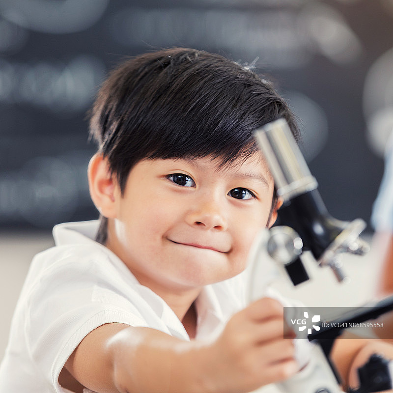展示显微镜的可爱小学生肖像图片素材