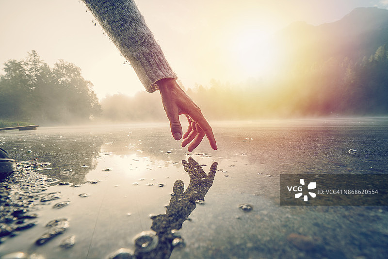 手指触摸瑞士的山间湖面图片素材