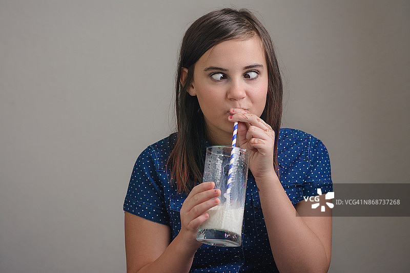 女孩用吸管喝牛奶，翻着白眼图片素材