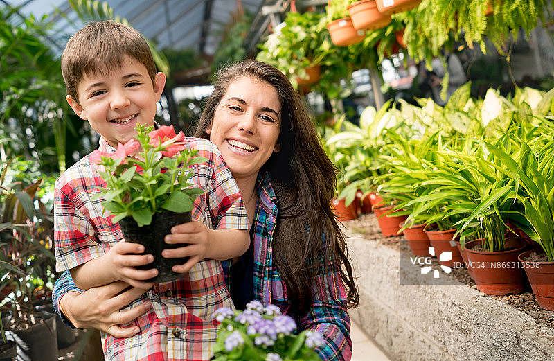 在花园中心看镜头的微笑母子肖像图片素材